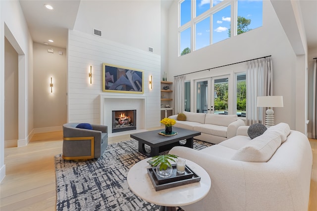 living room featuring built in features, a high ceiling, french doors, and light hardwood / wood-style floors