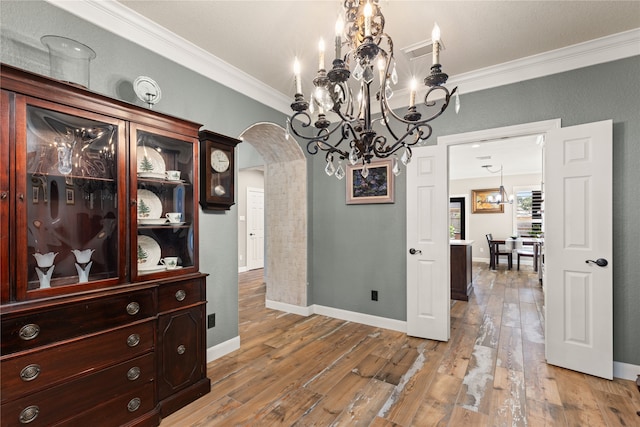 dining space with a notable chandelier, crown molding, and hardwood / wood-style flooring