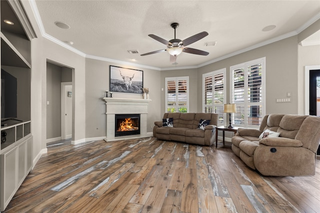 living room with a textured ceiling, wood-type flooring, crown molding, and ceiling fan