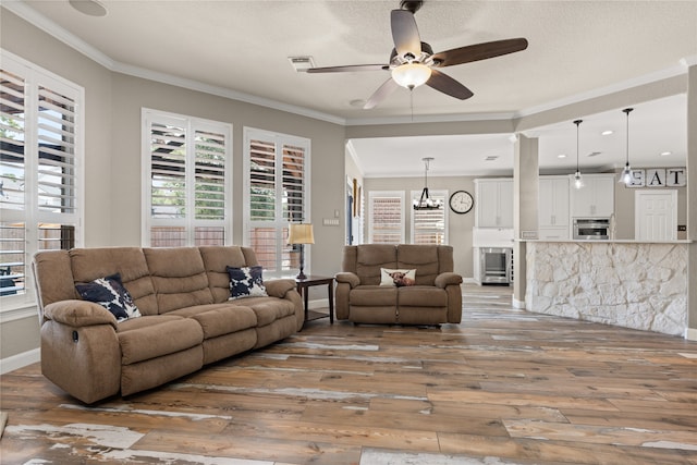 living room featuring ornamental molding, wood-type flooring, ceiling fan, and a textured ceiling