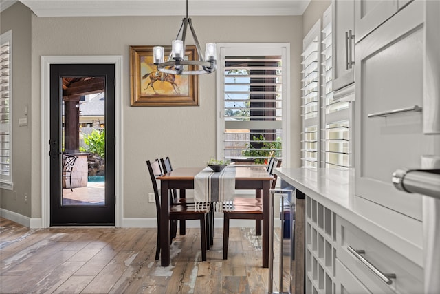 dining area featuring light wood-type flooring, crown molding, beverage cooler, and a notable chandelier