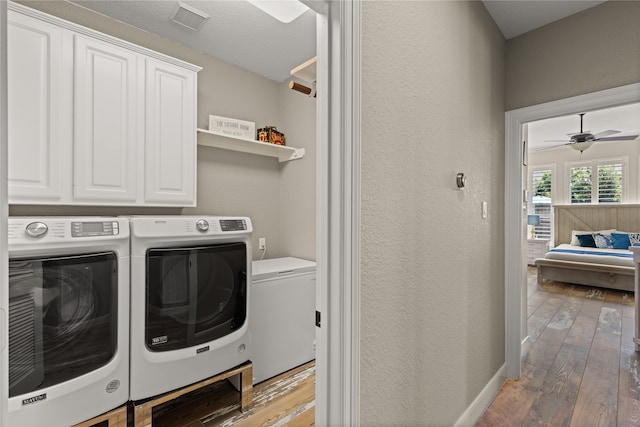 clothes washing area with washer and dryer, light hardwood / wood-style floors, ceiling fan, and cabinets