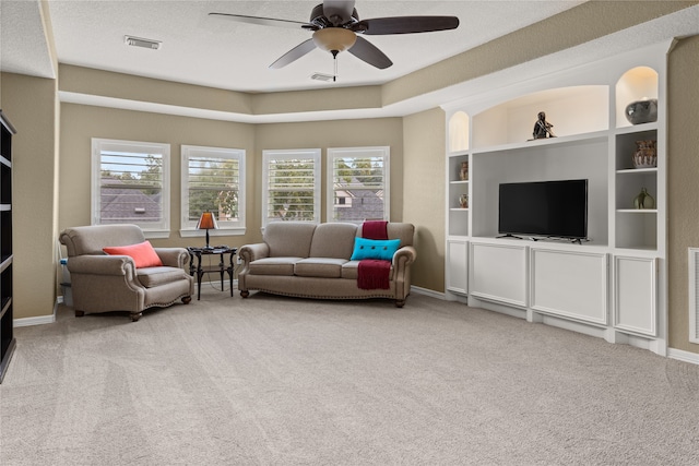 living room with light carpet, ceiling fan, and a textured ceiling