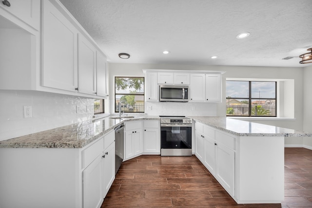 kitchen with dark wood-type flooring, light stone counters, tasteful backsplash, white cabinetry, and stainless steel appliances