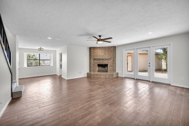 unfurnished living room featuring a fireplace, ceiling fan, hardwood / wood-style floors, and a textured ceiling