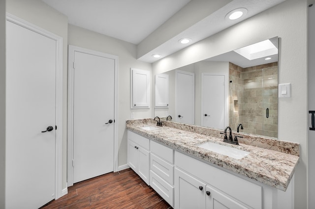 bathroom featuring hardwood / wood-style flooring, a skylight, an enclosed shower, and vanity