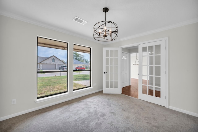 empty room featuring carpet flooring, a chandelier, ornamental molding, and french doors