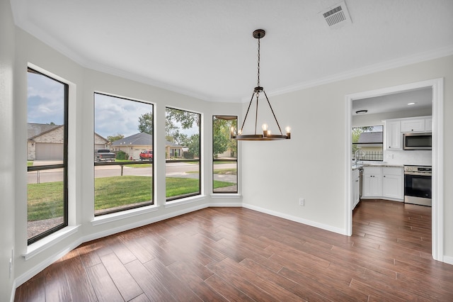 unfurnished dining area featuring sink, a notable chandelier, dark wood-type flooring, and ornamental molding