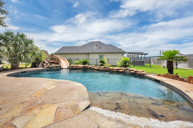 view of swimming pool with a water slide and a lawn