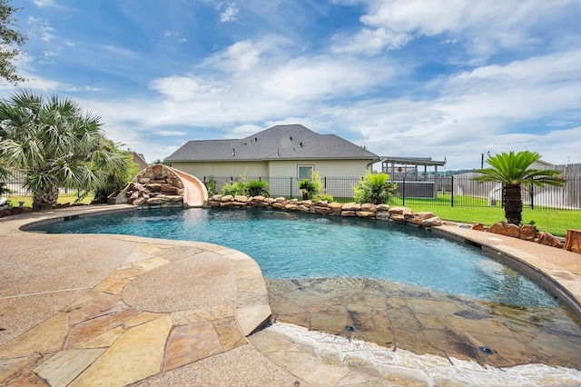 view of pool with fence, a yard, a water slide, a fenced in pool, and a patio area