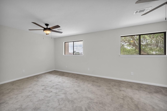 carpeted spare room featuring visible vents, baseboards, and a ceiling fan