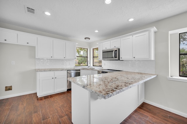 kitchen with decorative backsplash, white cabinetry, dark hardwood / wood-style floors, and stainless steel appliances