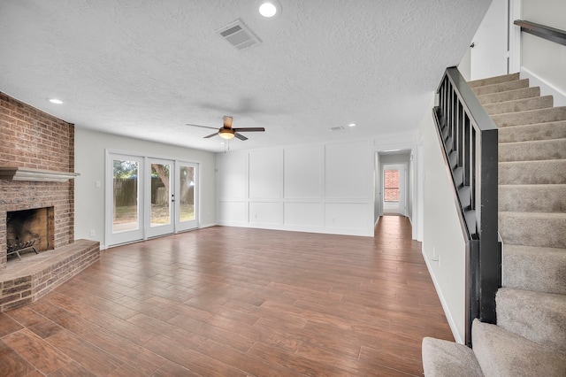 unfurnished living room featuring a fireplace, ceiling fan, hardwood / wood-style floors, and a textured ceiling