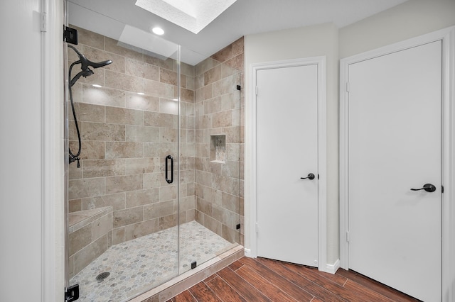 bathroom featuring an enclosed shower, hardwood / wood-style floors, and a skylight