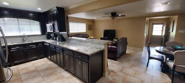 kitchen with sink, light tile patterned floors, ceiling fan, and light stone countertops