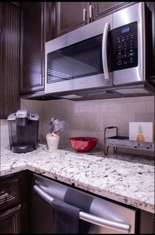 kitchen with decorative backsplash, light stone counters, and dark brown cabinets