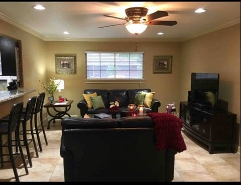 tiled living room featuring crown molding and ceiling fan