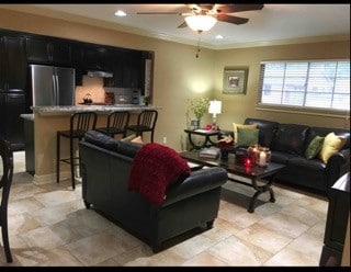 living room with ornamental molding, light tile patterned floors, and ceiling fan