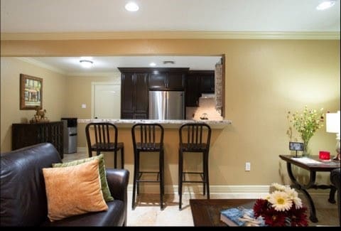 interior space with stainless steel refrigerator, a kitchen bar, kitchen peninsula, and crown molding