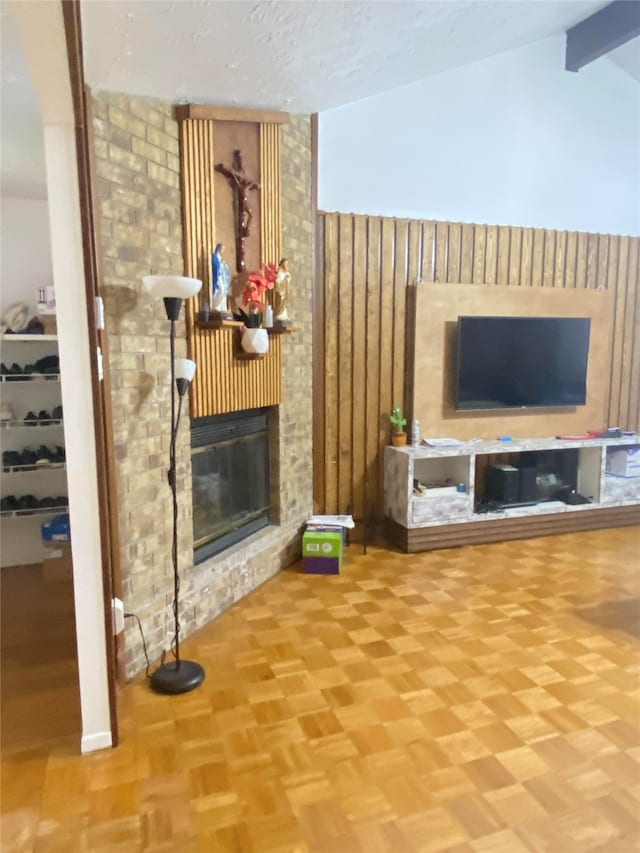 living room featuring vaulted ceiling with beams, a fireplace, brick wall, and parquet floors