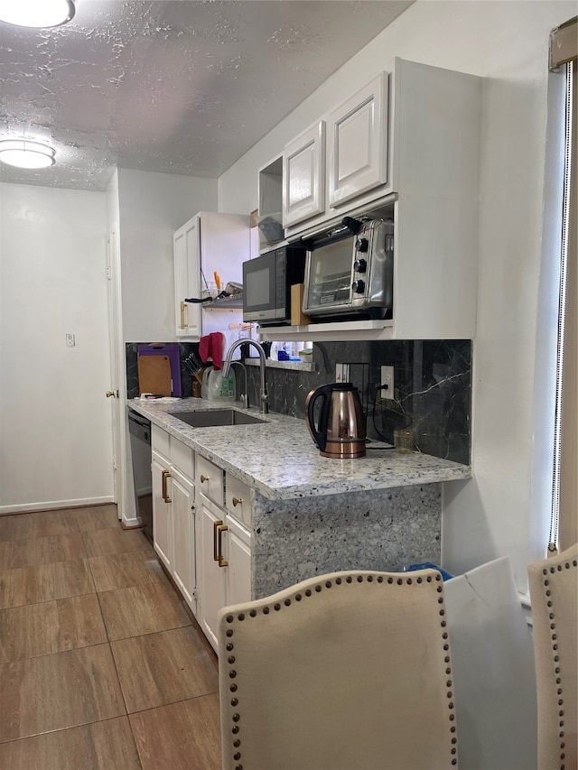 kitchen with white cabinetry, tasteful backsplash, sink, dishwasher, and light hardwood / wood-style flooring