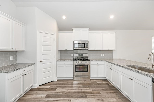 kitchen with sink, backsplash, light wood-type flooring, and stainless steel appliances