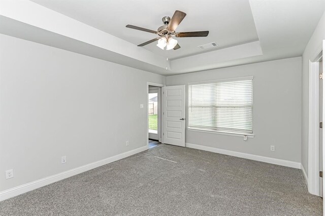 carpeted spare room with ceiling fan and a raised ceiling