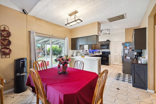 dining area featuring sink, a textured ceiling, and light tile patterned floors