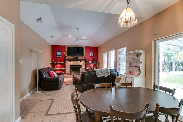 dining area featuring a healthy amount of sunlight, a fireplace, ceiling fan with notable chandelier, and vaulted ceiling