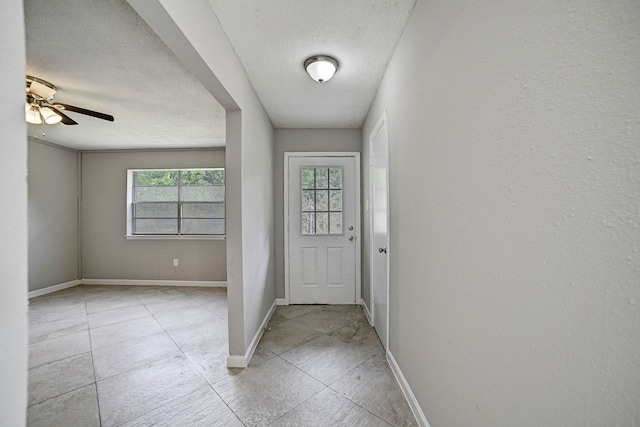 entryway featuring a textured ceiling, light tile patterned floors, and ceiling fan