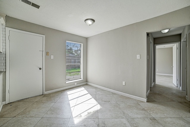 tiled empty room with a textured ceiling