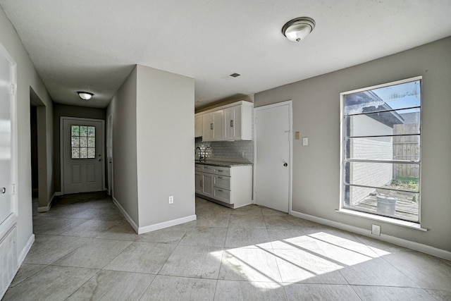 kitchen with white cabinets, light tile patterned flooring, tasteful backsplash, and plenty of natural light