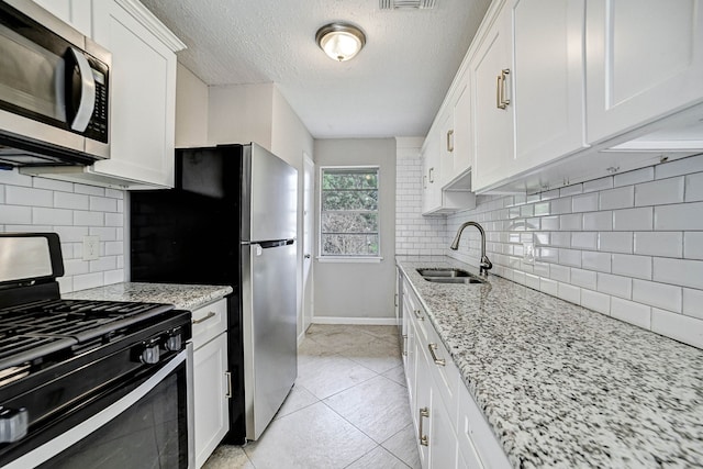 kitchen with white cabinets, sink, decorative backsplash, a textured ceiling, and black gas range