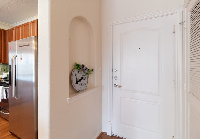 interior space featuring ornamental molding, light wood-type flooring, and a textured ceiling