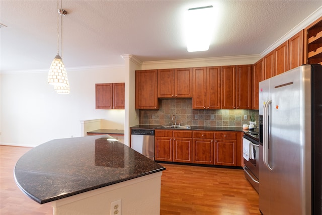 kitchen with appliances with stainless steel finishes, light hardwood / wood-style flooring, sink, pendant lighting, and ornamental molding