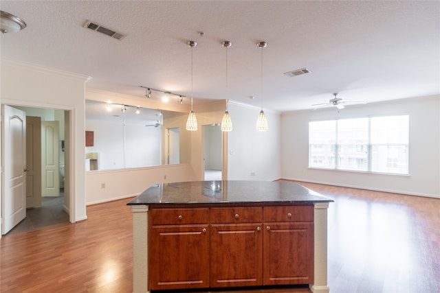 kitchen featuring light tile patterned flooring, a textured ceiling, crown molding, and ceiling fan