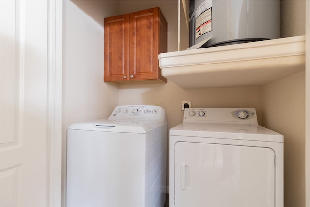 clothes washing area with water heater, cabinets, and washing machine and dryer