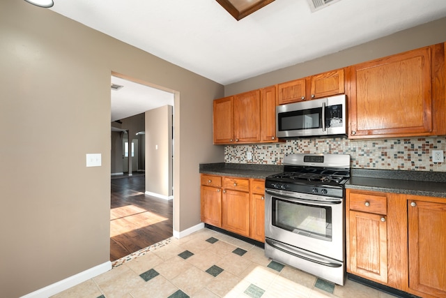 kitchen featuring stainless steel appliances, backsplash, and light wood-type flooring