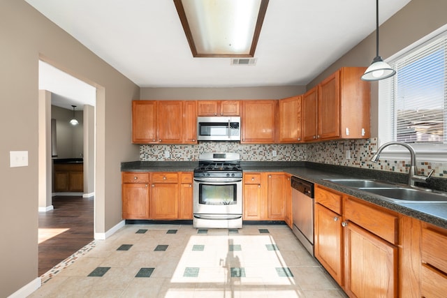 kitchen featuring light tile patterned flooring, tasteful backsplash, stainless steel appliances, hanging light fixtures, and sink