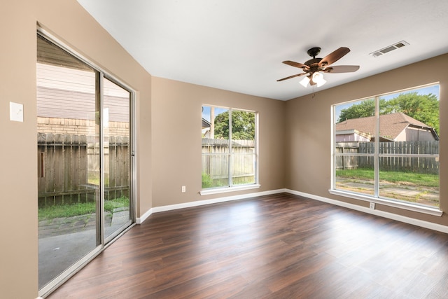 empty room with a ceiling fan, dark wood finished floors, visible vents, and baseboards