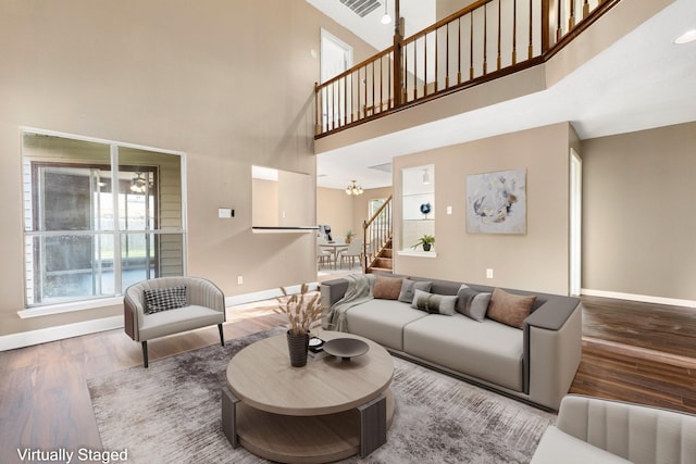 living area featuring stairs, a high ceiling, wood finished floors, and baseboards