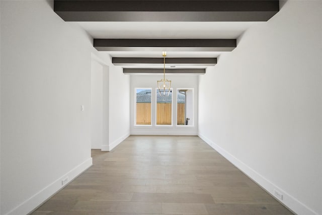 unfurnished dining area with a notable chandelier, beamed ceiling, and hardwood / wood-style floors