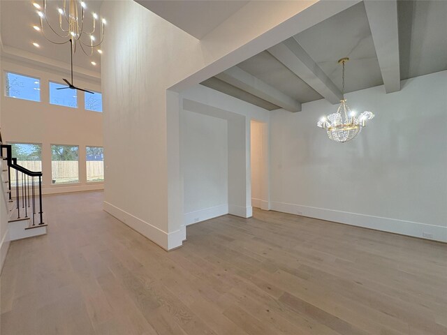 empty room featuring ceiling fan with notable chandelier, beamed ceiling, and light hardwood / wood-style flooring