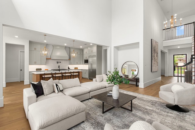 living room with recessed lighting, light wood finished floors, a notable chandelier, and baseboards