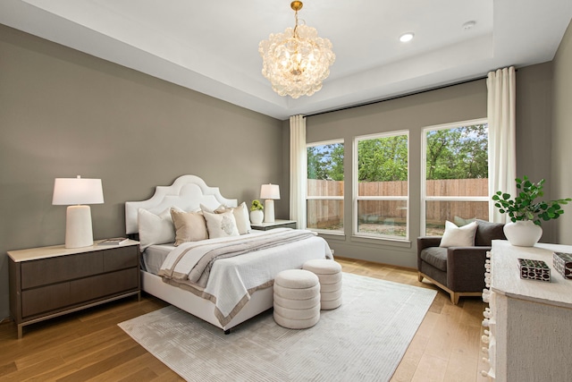 bedroom featuring a tray ceiling, multiple windows, and an inviting chandelier