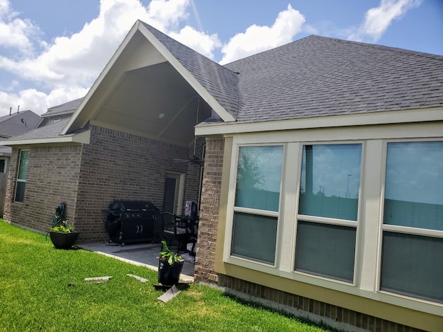 view of home's exterior featuring a patio, a yard, brick siding, and a shingled roof