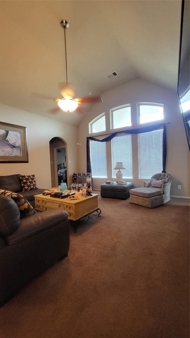 carpeted living room with ceiling fan and high vaulted ceiling