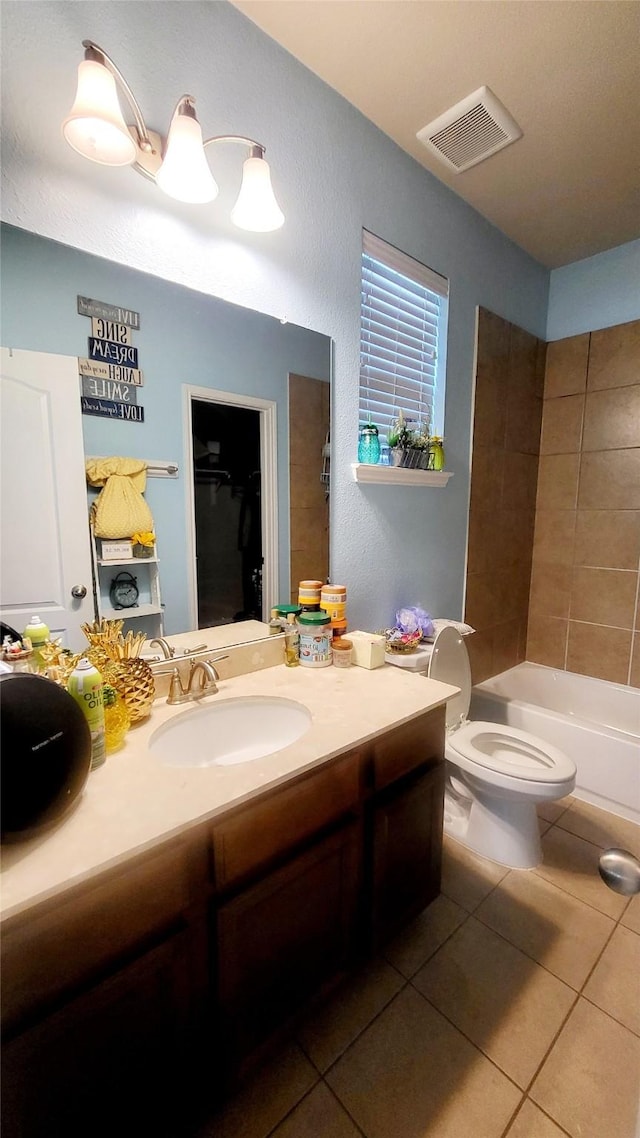 full bathroom with tile patterned flooring, vanity, tiled shower / bath, and toilet