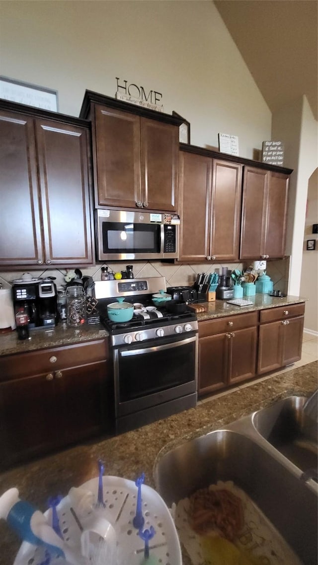 kitchen featuring dark brown cabinetry, sink, decorative backsplash, and appliances with stainless steel finishes