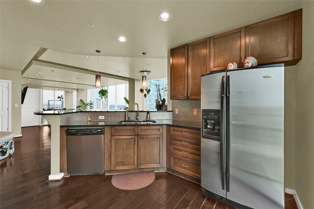 kitchen with appliances with stainless steel finishes, decorative light fixtures, sink, and dark hardwood / wood-style flooring